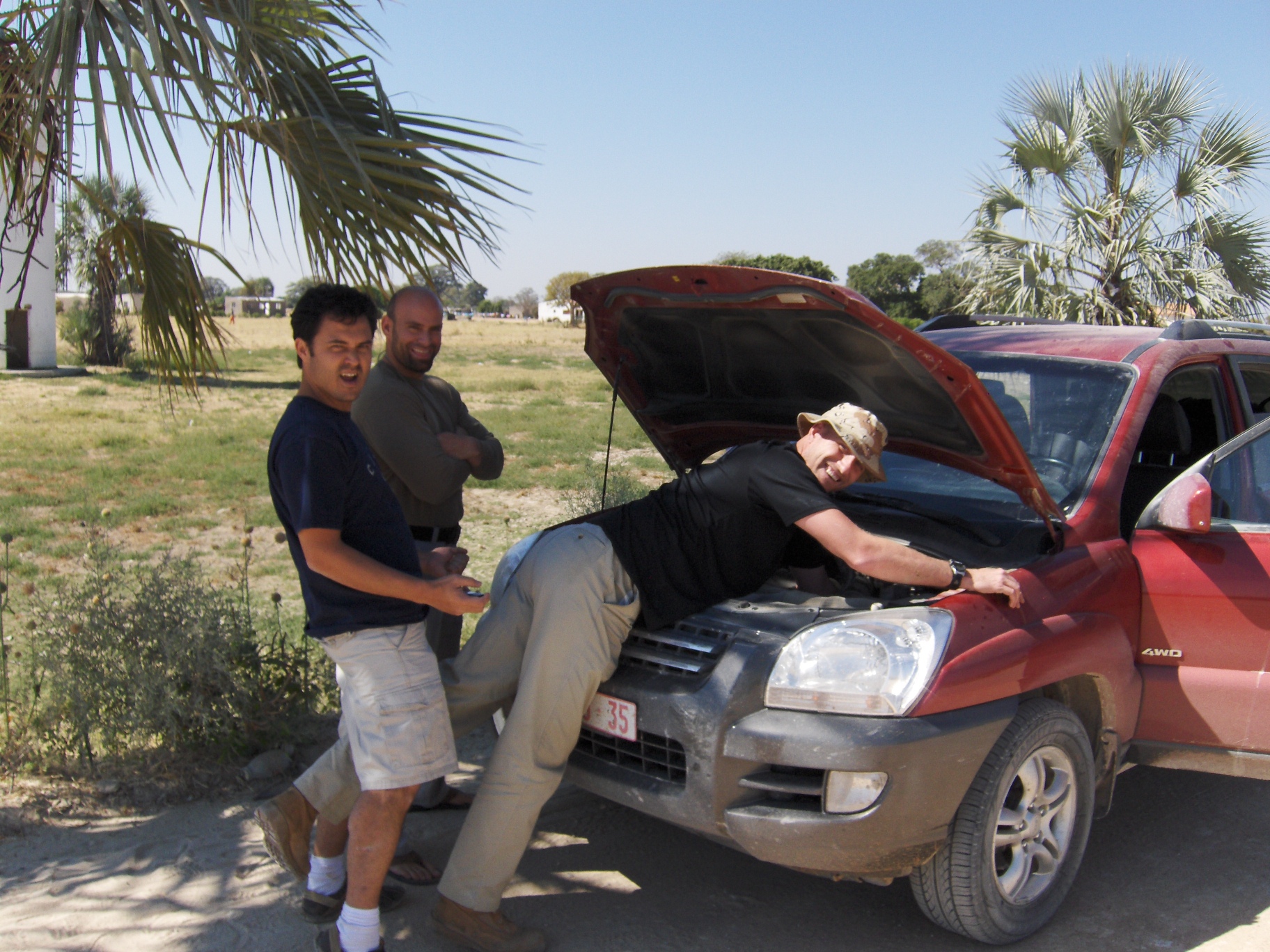 three guys fixing a car