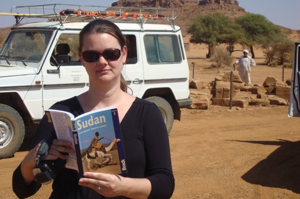girl reading guidebook in desert in sudan