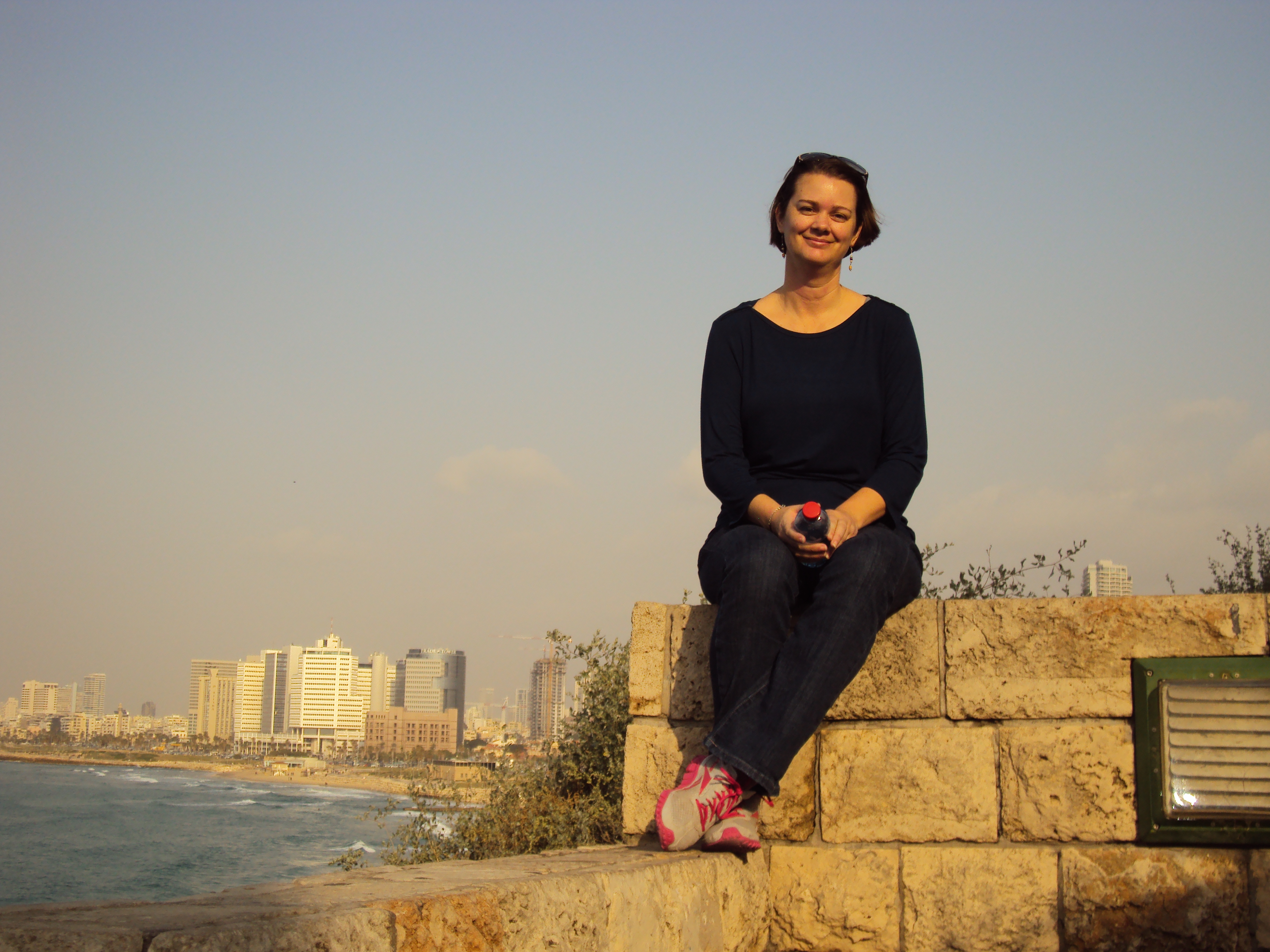 woman sitting on blocks with Tel Aviv Israel in background