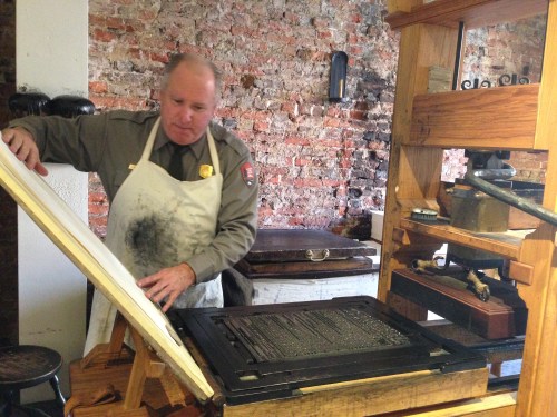 Park Ranger demonstrating a printing press at Ben Franklin's printing house