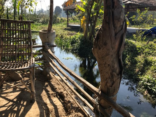 Wicker chair and railing along stream at farm in Rishikesh India